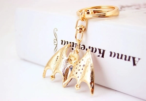 Close-up of gothic gold bat keychain featuring a central crystal and lobster clasp