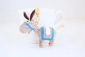 Close-up of a sparkling rhinestone donkey keychain with blue saddle and golden ring