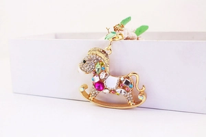 Détail d'un porte-clés cheval à bascule avec strass colorés et finition dorée