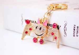 Macro shot of sparkling crystal rhinestones and pink enamel on golden cartoon bat keychain