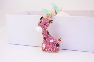 Gros plan d'un porte-clés girafe en strass roses avec base dorée et détails en émail noir