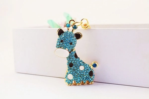 Gros plan d'un porte-clés girafe doré avec strass bleu foncé sur une boîte blanche