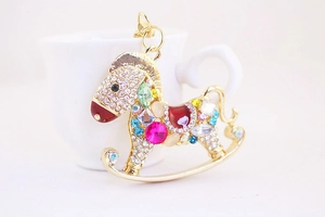 Gros plan sur porte-clés cheval à bascule doré avec cristaux colorés et strass brillants