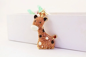 Détail du porte-clés girafe avec strass orange et base en métal doré brillant
