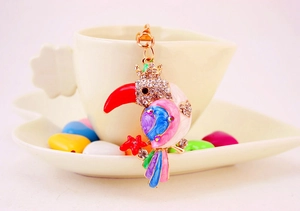 Detailed macro view of crystal parrot keychain hanging on a white coffee cup rim
