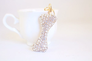 Macro detail of a sparkling golden bone-shaped keychain encrusted with crystal rhinestones