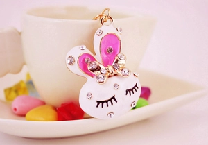 Macro detail of cute rhinestone rabbit pendant with enamel finish and gold bow