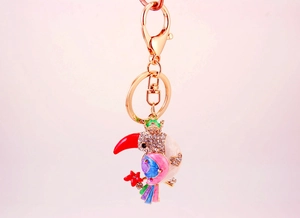 Close-up of colorful toucan keychain with vibrant crystals and polished gold-plated metal