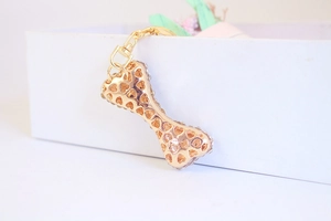 Macro shot of gold alloy bone keychain featuring hollow heart patterns and sparkling rhinestones