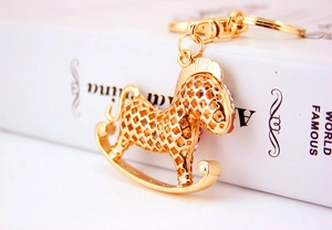 Détail d'un porte-clés cheval à bascule doré avec découpes trèfle et strass fins
