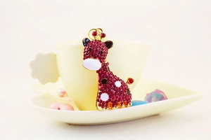 Détail du pendentif girafe en métal doré serti de strass roses et de points en émail