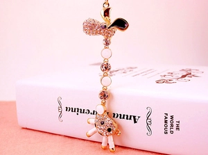 Detail of a golden sheep keychain with rhinestones resting on a white book cover