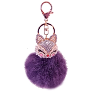 Close-up of sparkling rhinestone fox head and purple faux fur pompom keychain detail