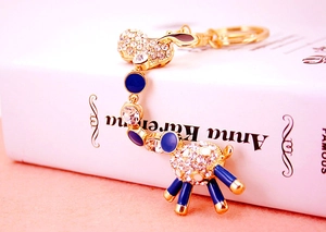 Detailed macro view of a gold-plated giraffe keychain with white crystals and blue enamel dots