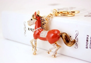 Close-up of red enamel horse keychain with gold plating and white rhinestones