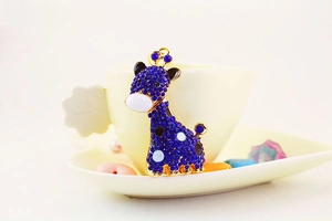 Vue détaillée d'un porte-clés girafe orné de strass bleus sur le bord d'une tasse