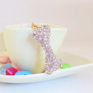 Sparkly crystal bone keychain charm with gold metal plating on a ceramic cup edge