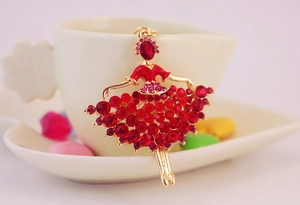 Detailed close-up of a golden ballet dancer keychain with sparkling red crystal accents