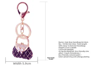 Detail of purple handbag keychain with pink rhinestones and a white bow decoration