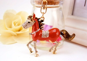 Macro detail of red enamel horse keychain with sparkling crystals and gold hardware