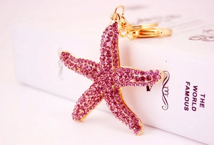 Detailed close-up of a starfish keychain with purple rhinestones and gold metal finish