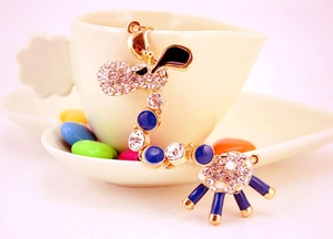 Close-up of golden giraffe keychain with blue enamel and sparkling crystals on a cup