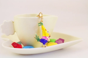 Gros plan d'un porte-clés oiseau coloré en émail suspendu à une tasse en céramique