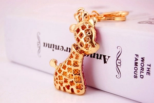 Détail d'un porte-clés girafe doré avec strass roses et fermoir mousqueton sur livre