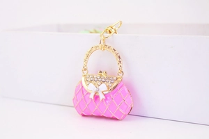 Macro detail of pink enamel handbag keychain with gold trim and crystal rhinestones