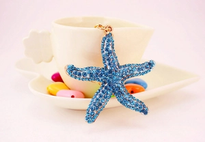 Macro detail of starfish keychain featuring light blue rhinestones on a gold metal frame