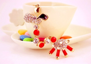 Close-up of golden giraffe keychain with white crystals and red enamel on a white cup