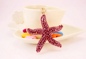 Detail of starfish keychain with purple and pink rhinestones on a gold alloy base