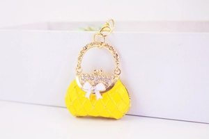 Macro shot of yellow quilted handbag keychain with white rhinestones and a bow detail