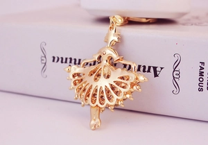Exquisite hollow ballerina keychain pendant with golden finish on book background