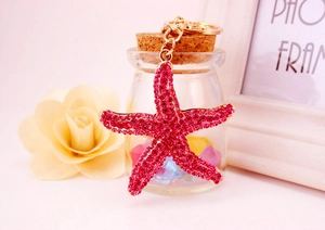 Detail of rose pink rhinestone starfish keychain with gold metal link on prop background