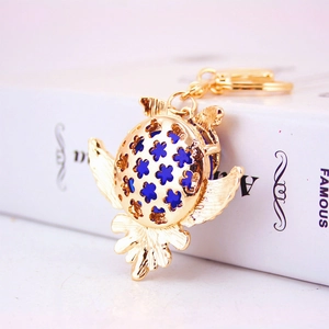 Porte-clés hibou doré avec ailes en filigrane et centre bleu sur un livre blanc