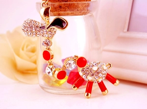 Macro shot of gold-plated sheep charms with white crystals and red enamel details