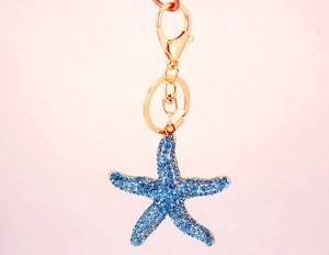 Macro view of blue rhinestone starfish keychain with polished golden lobster clasp and ring