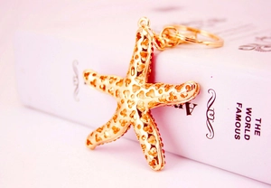 Detail view of gold starfish keychain with red rhinestones and hollow wave pattern