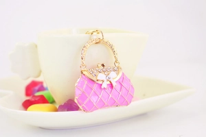 Detailed view of pink enamel handbag keychain with rhinestones and golden bow accent