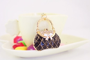 Detail of black enamel handbag keychain with white rhinestones and golden hardware