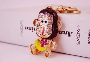 Détail d'un porte-clés singe étincelant orné de cristaux et strass rouges sur métal doré