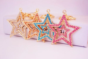 Close-up of four colorful double-layered star keychains with glittering rhinestones