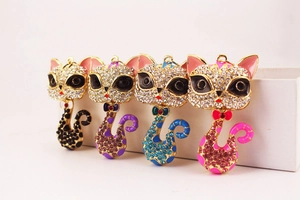 Détail de quatre porte-clés chat colorés en alliage avec strass et émail poli