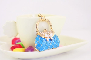Detail of light blue handbag keychain with rhinestone bow and gold quilted pattern