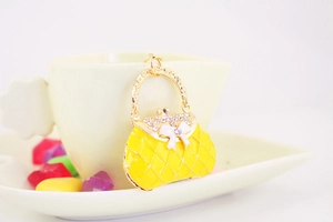Detailed close-up of a yellow enamel handbag charm with rhinestones and a white bow decoration