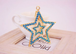 Détail du porte-clés triple étoile dorée avec strass bleus et anneau métallique