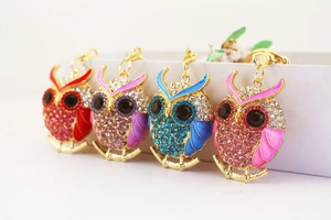 Detail of four colorful rhinestone owl keychains in red, purple, blue, and pink colors