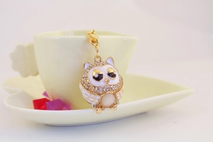 Detailed view of an owl pendant featuring crystal wings and yellow gemstone on a cup