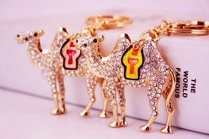Close-up of a sparkling gold camel keychain with white rhinestones and enamel details